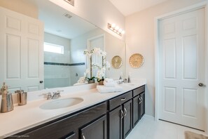 A modern bathroom with two sinks, dark cabinetry, and decorative wall art. - 9001fkw Amazing 7 Bedroom 5 Bathroom Solara (Kissimmee)