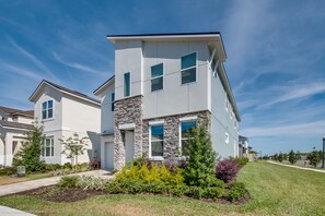 A modern two-story house with a stone facade, large windows, and a well-maintained lawn. - 9001fkw Amazing 7 Bedroom 5 Bathroom Solara (Kissimmee)