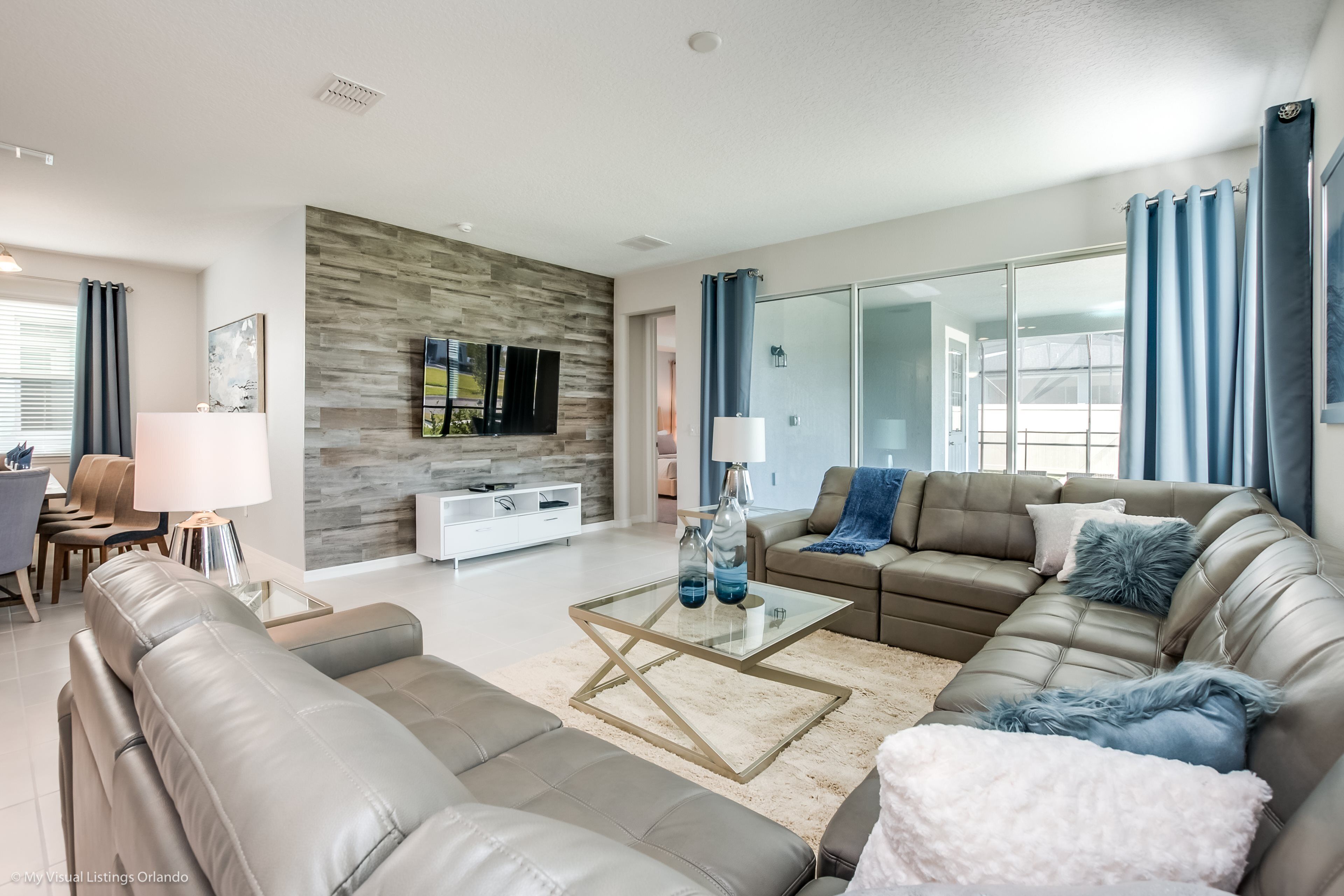 A modern living room with a leather sofa, a glass coffee table, and a stone accent wall.