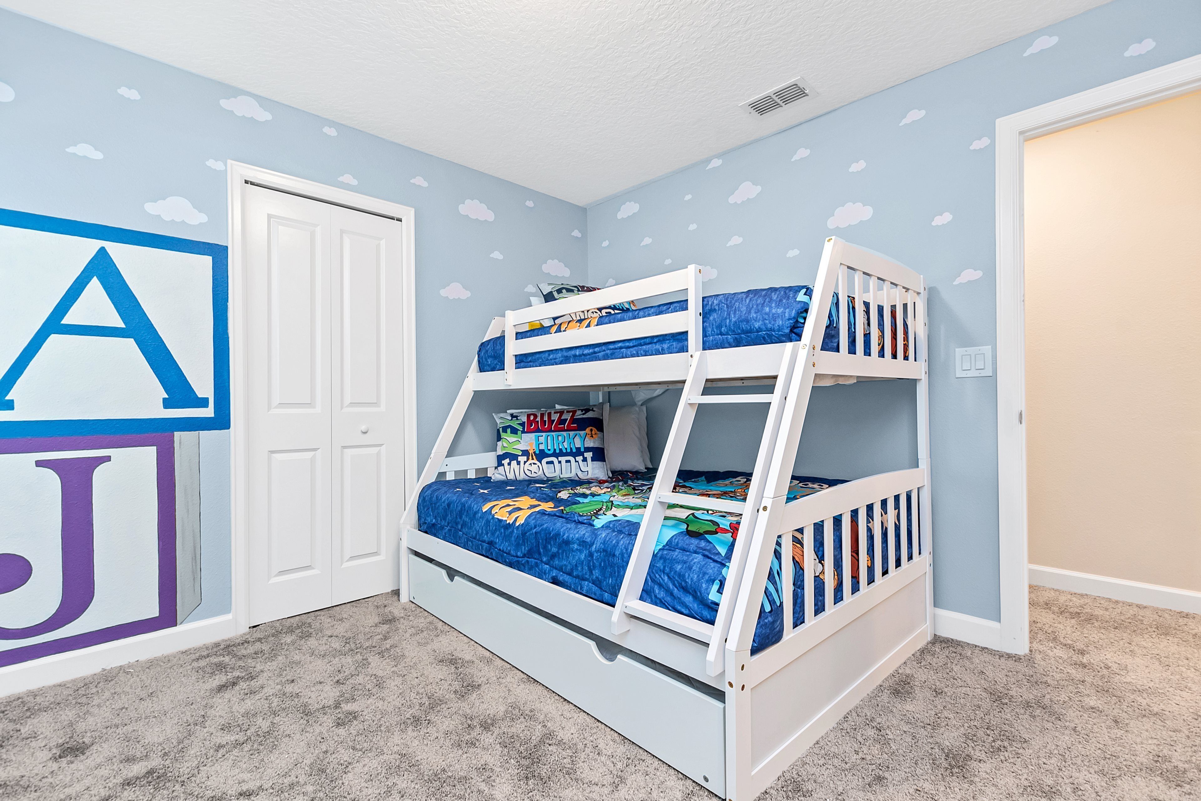 A bunk bed with a blue and white design, a door, and a wall with a large 'A' and 'J' painted on it.