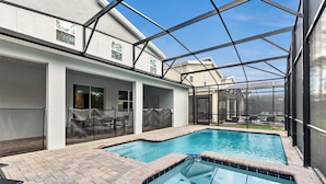 A swimming pool with a glass enclosure, brick flooring, and outdoor seating. - Family Friendly! 6bed 5Ba Villa with Pool (Kissimmee)