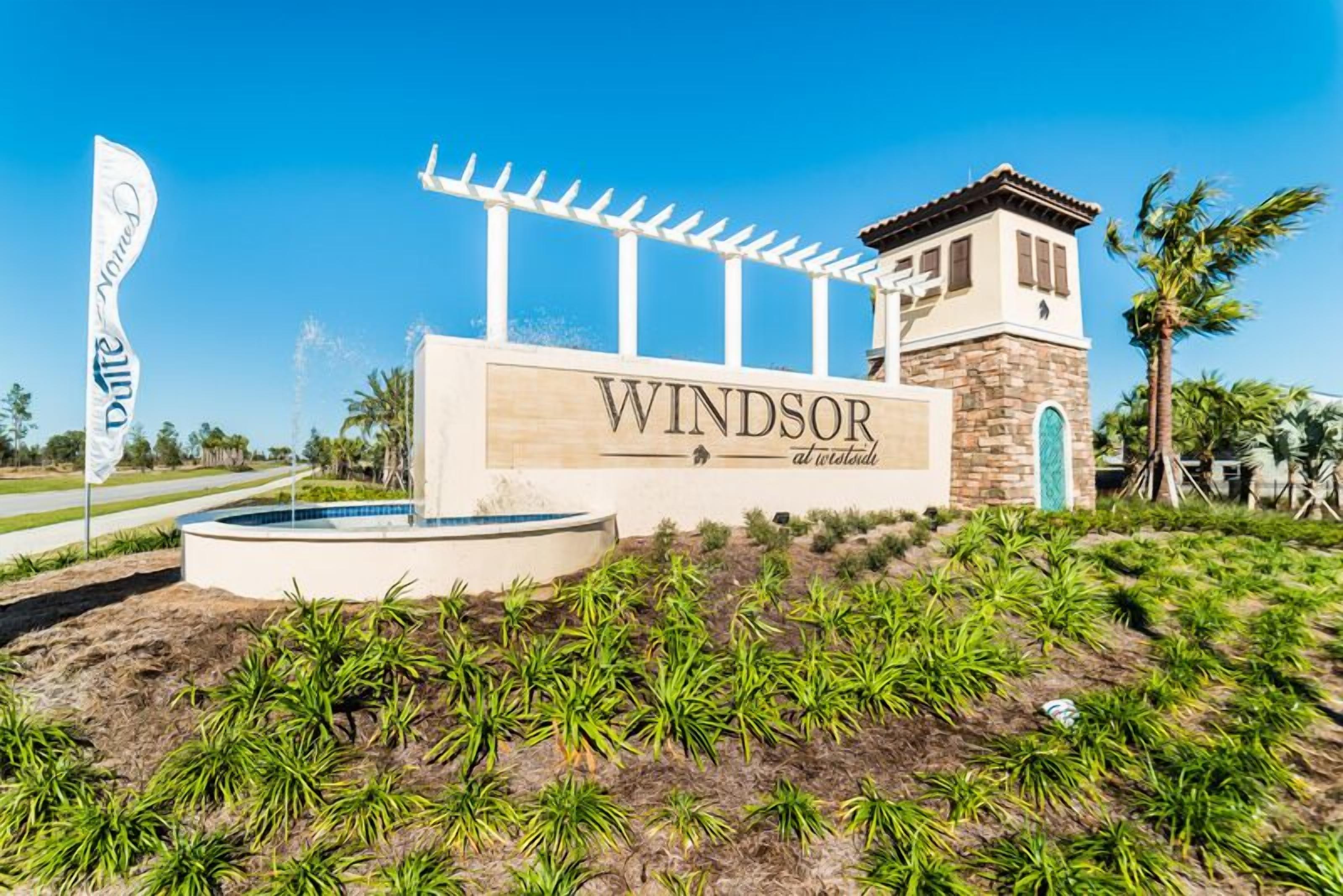 A sign for 'Windsor at the World Golf Club' with a pergola structure, a pool, and landscaped greenery.