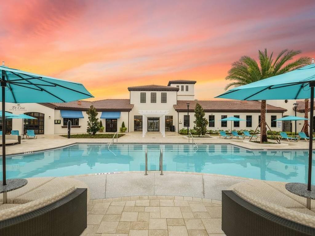 Un hotel con piscina, mobiliario exterior y vistas al atardecer.