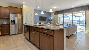 A modern kitchen with a large island, stainless steel appliances, and pendant lighting. - Lake View Villa (Kissimmee)