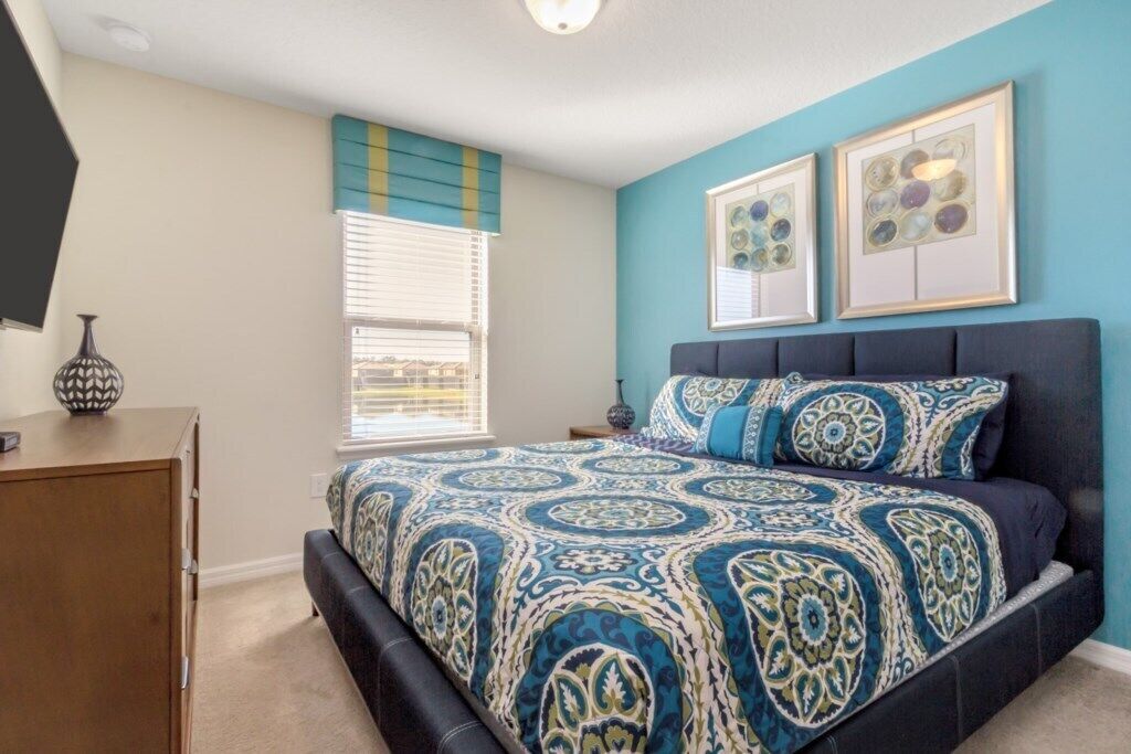 A bedroom with a bed, a nightstand, a dresser, and two framed pictures on the wall.
