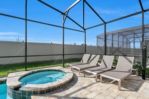 A covered outdoor area with a hot tub and lounge chairs. - 9 BD 6,5 BH Pool, Spa & Game Room (Kissimmee)