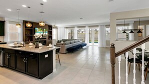 A spacious living area with a large island, dark cabinetry, and a staircase leading to another level. - 9 BD 6,5 BH Pool, Spa & Game Room (Kissimmee)