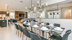A modern dining area with a glass table set for six, surrounded by dark upholstered chairs. - 9 BD 6,5 BH Pool, Spa & Game Room (Kissimmee)