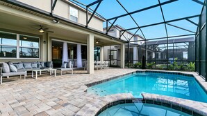 A pool area with a glass-enclosed patio, outdoor seating, and a hot tub. - 9 BD 6,5 BH Pool, Spa & Game Room (Kissimmee)