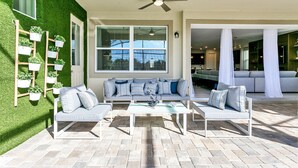 A modern outdoor living area with a sofa set, a coffee table, and a ceiling fan. - 9 BD 6,5 BH Pool, Spa & Game Room (Kissimmee)