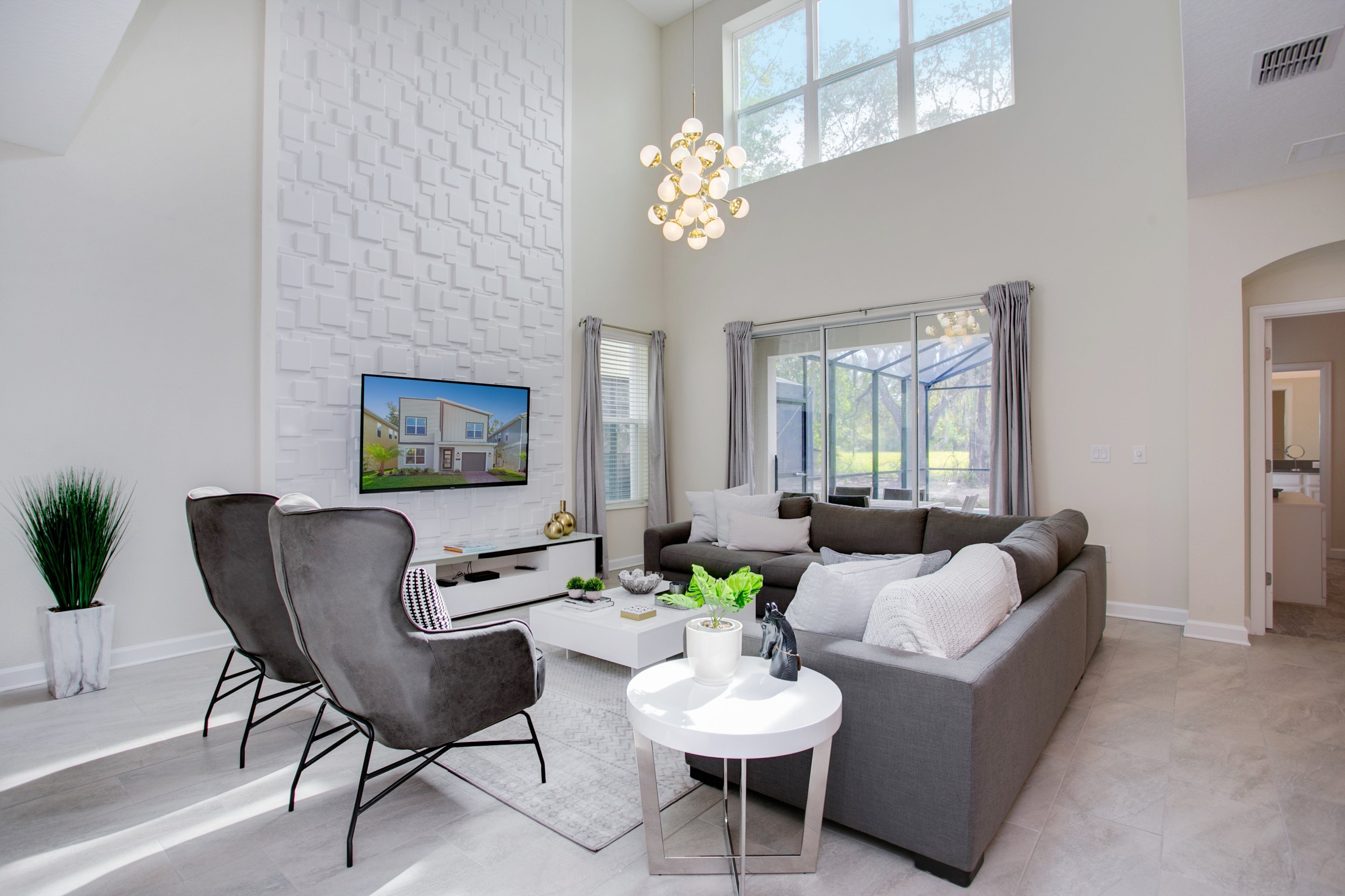 A modern living room with a grey sofa, a white coffee table, and a TV mounted on the wall.
