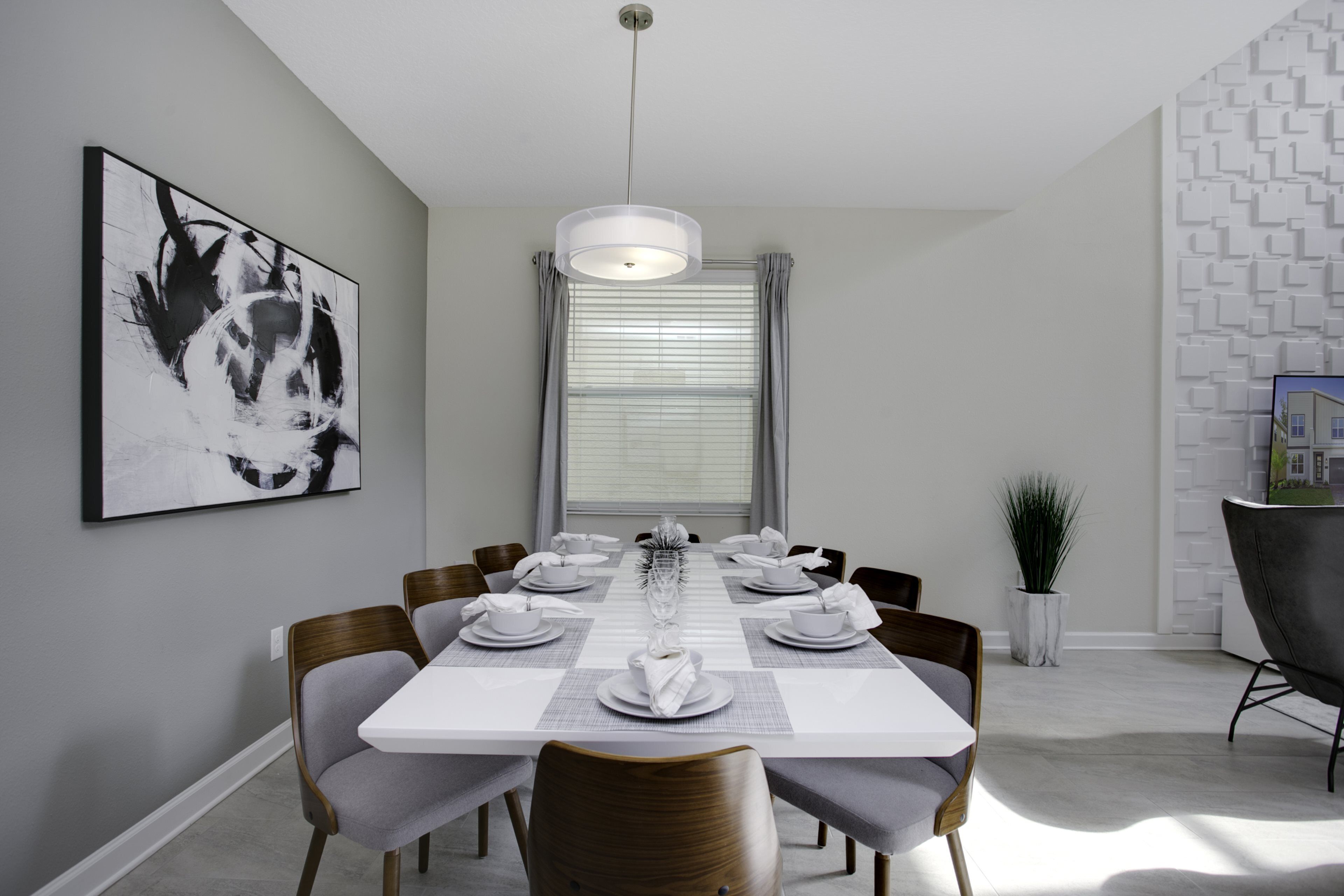Une salle à manger moderne avec une table blanche dressée pour six personnes, entourée de chaises en bois.