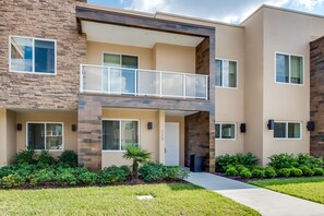 A modern two-story apartment building with a balcony, large windows, and a well-maintained lawn. - 3139brasillia (Kissimmee)