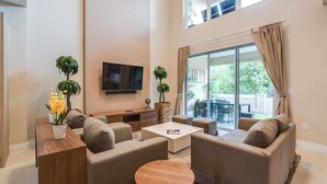 A spacious living room with a flat-screen TV, beige sofas, a coffee table, and potted plants. - 3139brasillia (Kissimmee)