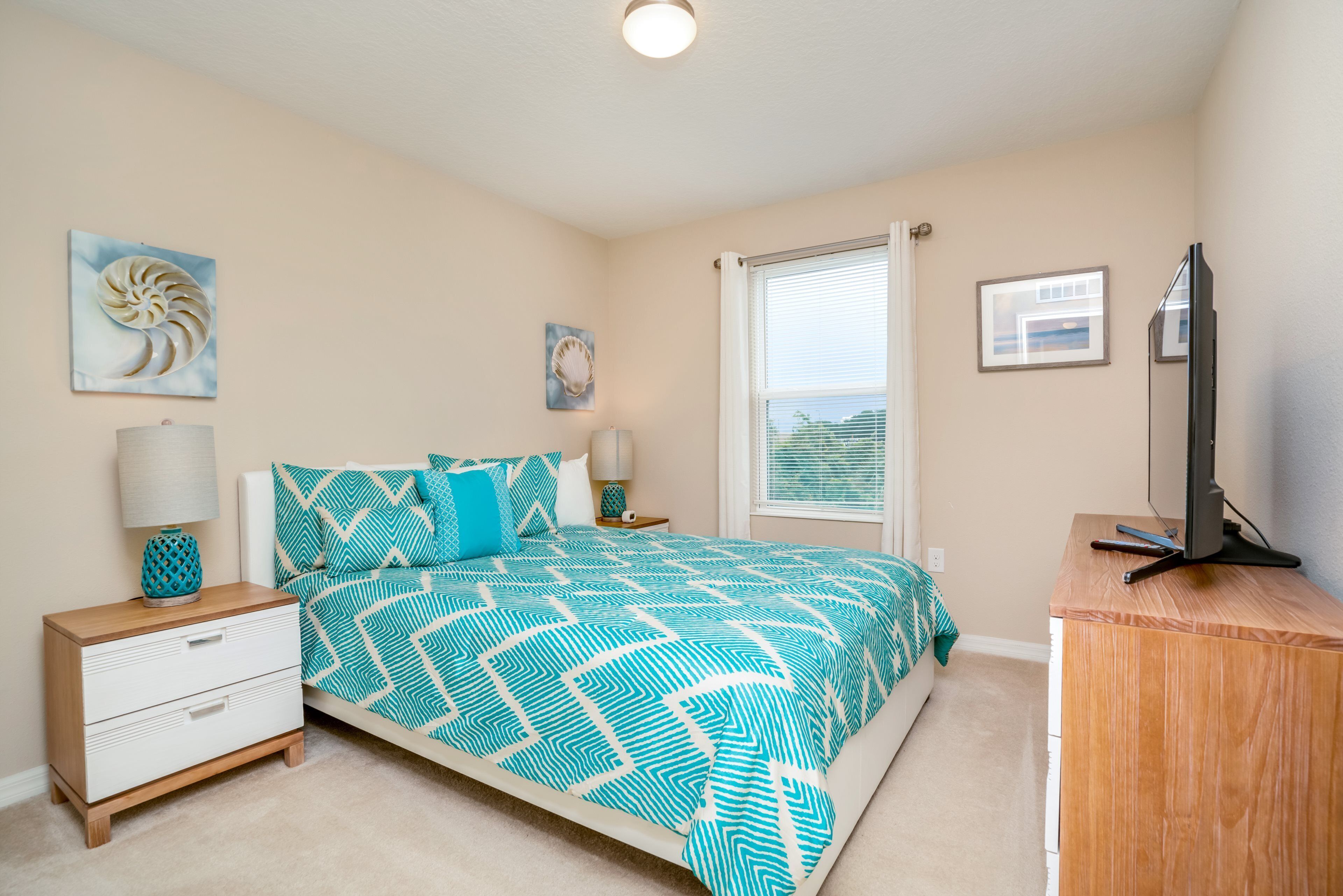 A bedroom with a bed, nightstands, a dresser, and a television.