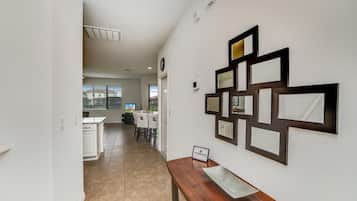 A hallway with a dining area in the background, a wooden bench, and wall-mounted mirrors.