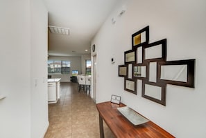 A hallway with a dining area in the background, a wooden bench, and wall-mounted mirrors. - 2586rose (Davenport)
