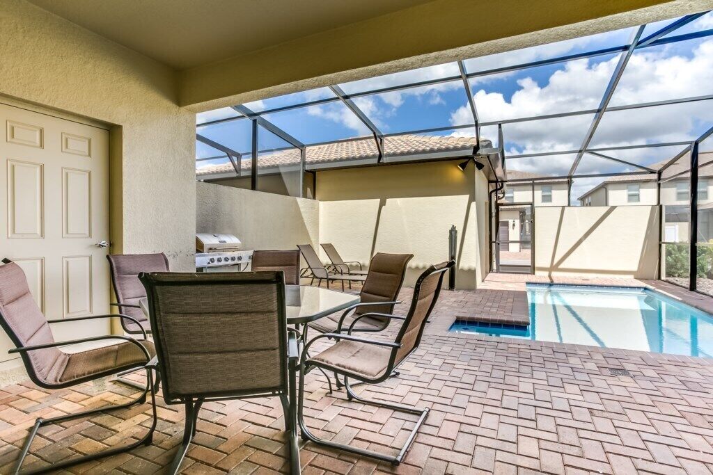 An outdoor patio with a pool, a grill, and seating.