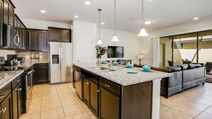 A modern kitchen with dark cabinetry, a granite countertop, and a central island. - 8932adriatico (Kissimmee)