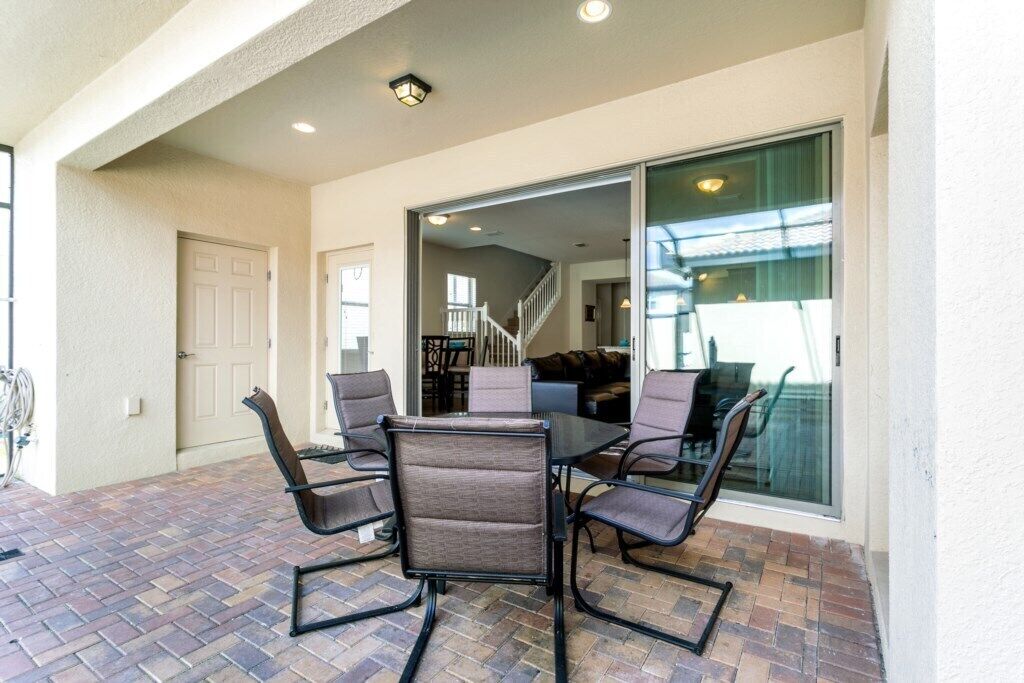 An outdoor patio with a table and chairs, a door, and a view into the house.
