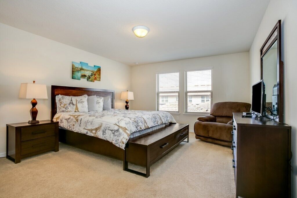 A bedroom with a bed, nightstands, a chair, a dresser, and a TV.