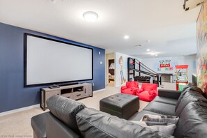 A modern living room with a large flat-screen TV, comfortable seating, and a Toy Story-themed wall.
