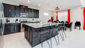 A modern kitchen with dark cabinetry, stainless steel appliances, and a central island with bar stools.