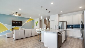 A modern kitchen with a central island, white cabinetry, and stainless steel appliances.