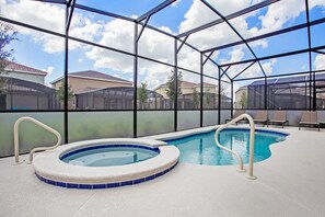 An indoor swimming pool with a hot tub, surrounded by a glass enclosure, and a view of residential buildings. - 7 Bed 5 Ba Villa with Games, Pool & Spa (Davenport)