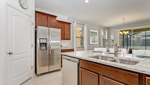 A modern kitchen with stainless steel appliances, wooden cabinets, and a granite countertop. - 7 Bed 5 Ba Villa with Games, Pool & Spa (Davenport)