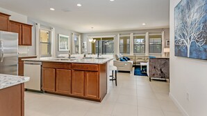 A spacious kitchen with a central island, wooden cabinets, and a dishwasher. - 7 Bed 5 Ba Villa with Games, Pool & Spa (Davenport)