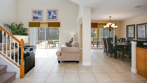 A spacious living area with a staircase, a dining area with chairs and a table, and a kitchen area with a counter and chairs. - 2251victo (Davenport)
