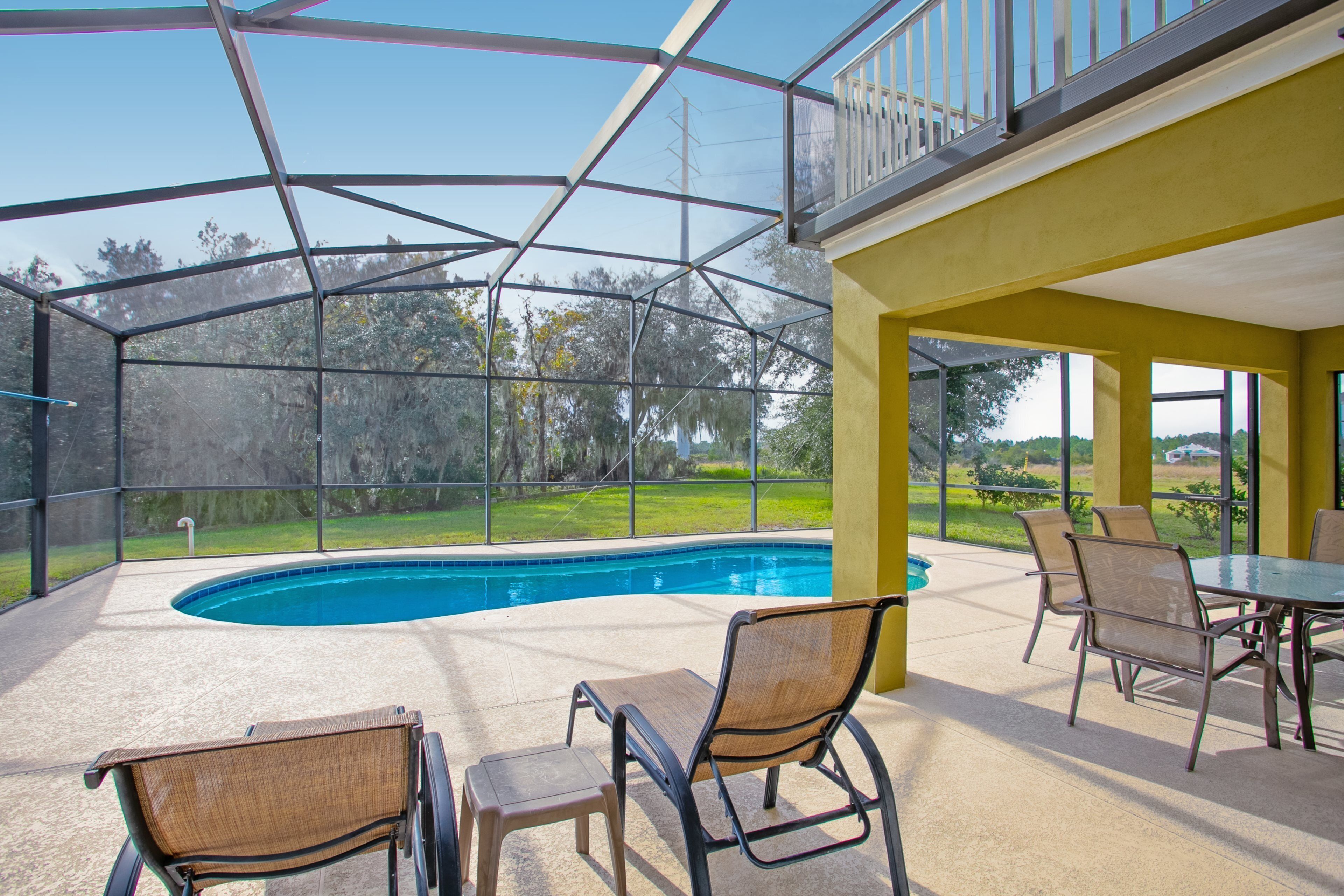 A covered outdoor area with a pool, chairs, and a table.