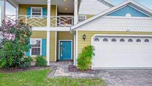 A two-story house with a blue door, a garage, and a balcony. - 2251victo (Davenport)