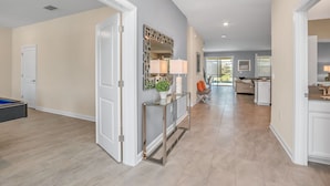 A spacious hallway with a modern console table, a decorative mirror, and a door leading to another room. - 4559naluxury Lake View 8 BR Villa With Games Room (Kissimmee)