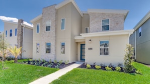 A modern two-story residential building with a stone facade, a blue door, and a well-maintained lawn. - 4559naluxury Lake View 8 BR Villa With Games Room (Kissimmee)
