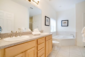 A modern bathroom with two sinks, a large mirror, a bathtub, and wooden cabinetry. - 2131victoria (Davenport)