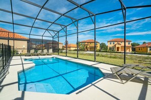 Une piscine offrant une vue dégagée sur les maisons environnantes, entourée d’une clôture en métal.