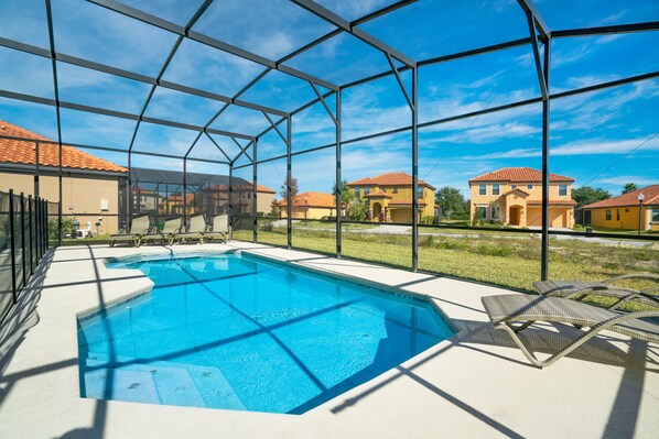 Una piscina con vista despejada de las casas circundantes y una estructura de valla metálica.