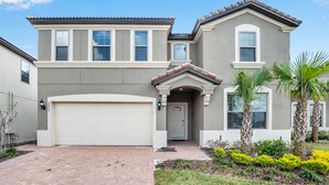 A two-story house with a garage, a front entrance with a door, and a small garden with palm trees. - 8856bengal (Kissimmee)