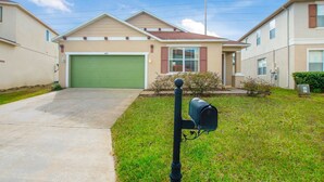 A residential house with a green garage door, a mailbox, and a well-maintained lawn. - 1418pine (Davenport)