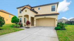 A two-story house with a beige facade, a tiled roof, and a garage. - 2629rose (Davenport)