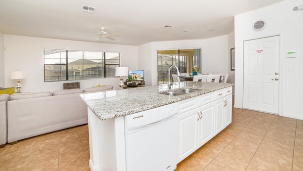 A spacious kitchen with a large island, white cabinetry, and a built-in dishwasher. - 2629rose (Davenport)