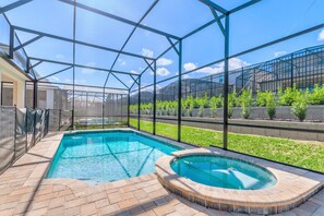 Une piscine entourée d’une paroi de verre, elle-même bordée d’une terrasse en briques.