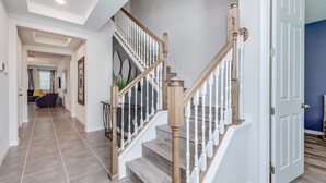 A modern home interior with a staircase, a hallway, and a living area.