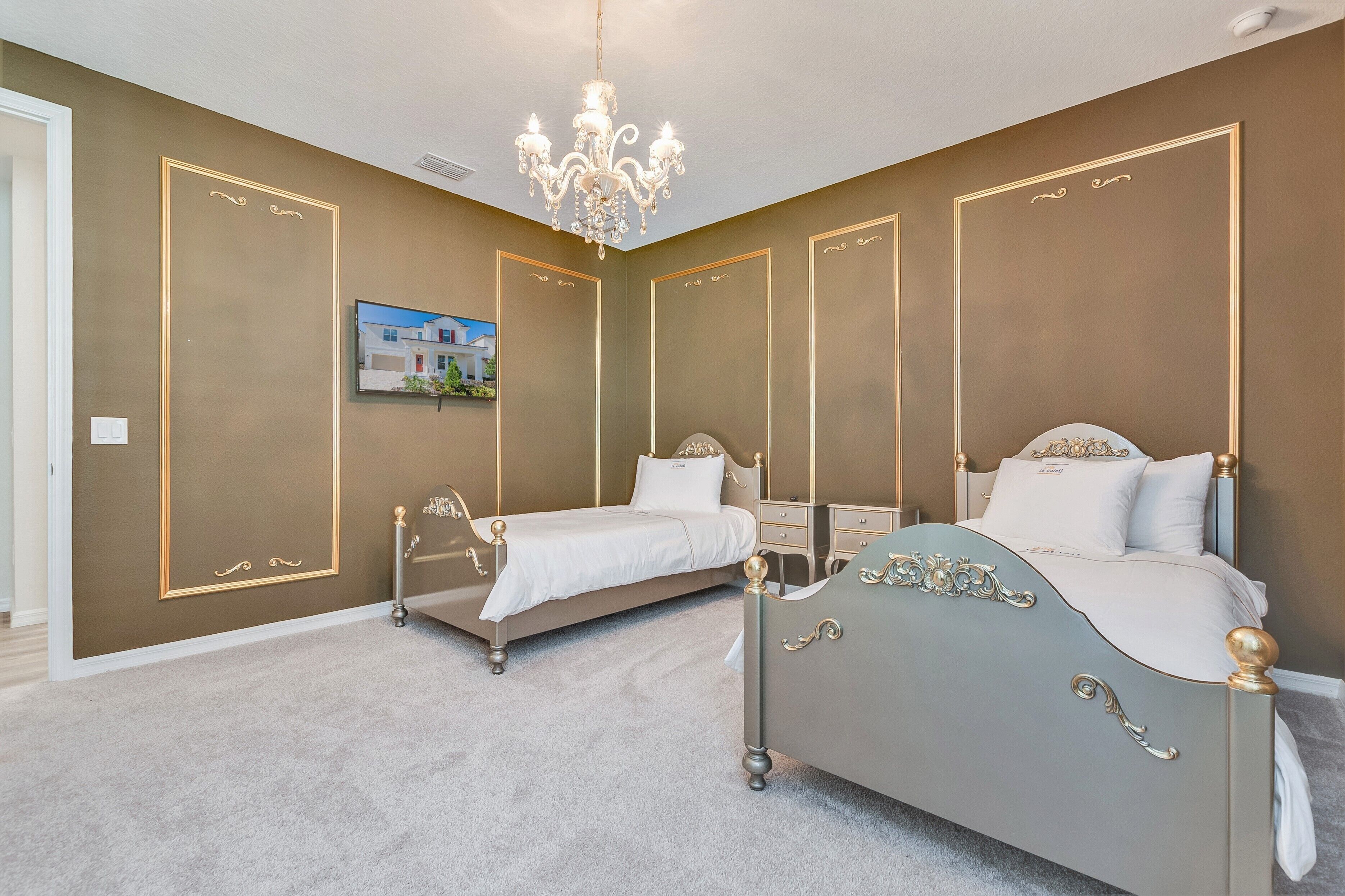 Une chambre avec deux lits, un lustre et un tableau encadré au mur.