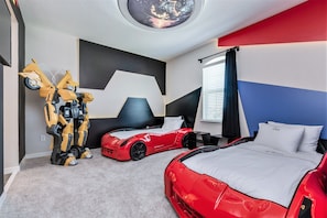 Ett sovrum med två sängar, ett tak med ett runt fönster och en robotfigur.
