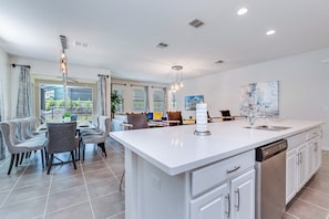 Enjoy meals in this well-lit kitchen with a central island and dishwasher, surrounded by a dining table and chairs.