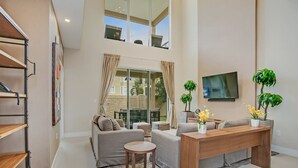 A spacious living area with a sofa set, a wooden coffee table, and a TV mounted on the wall. - Modern Magic Village Resort Townhome (Kissimmee)