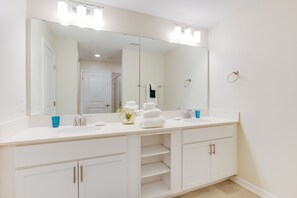 Une salle de bain moderne avec un grand miroir, deux lavabos et des placards intégrés.
